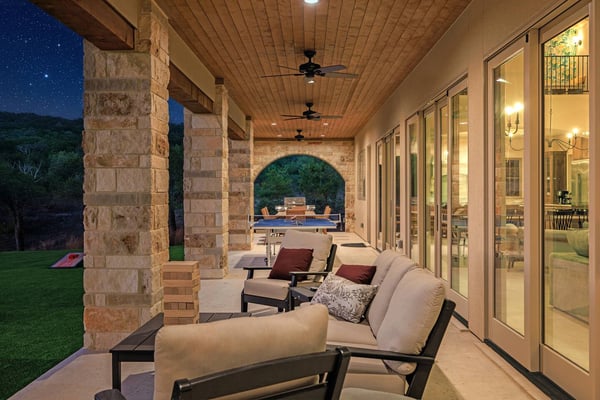 Outdoor patio with stone fire pit, wooden seating, and valley view through oak trees